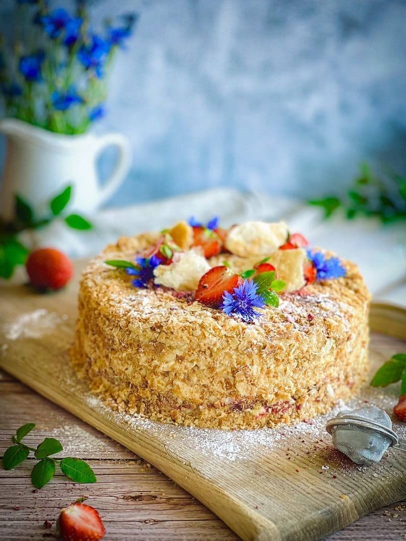 A tempting Napoleon cake adorned with strawberries and cornflowers, perfect for dessert lovers.