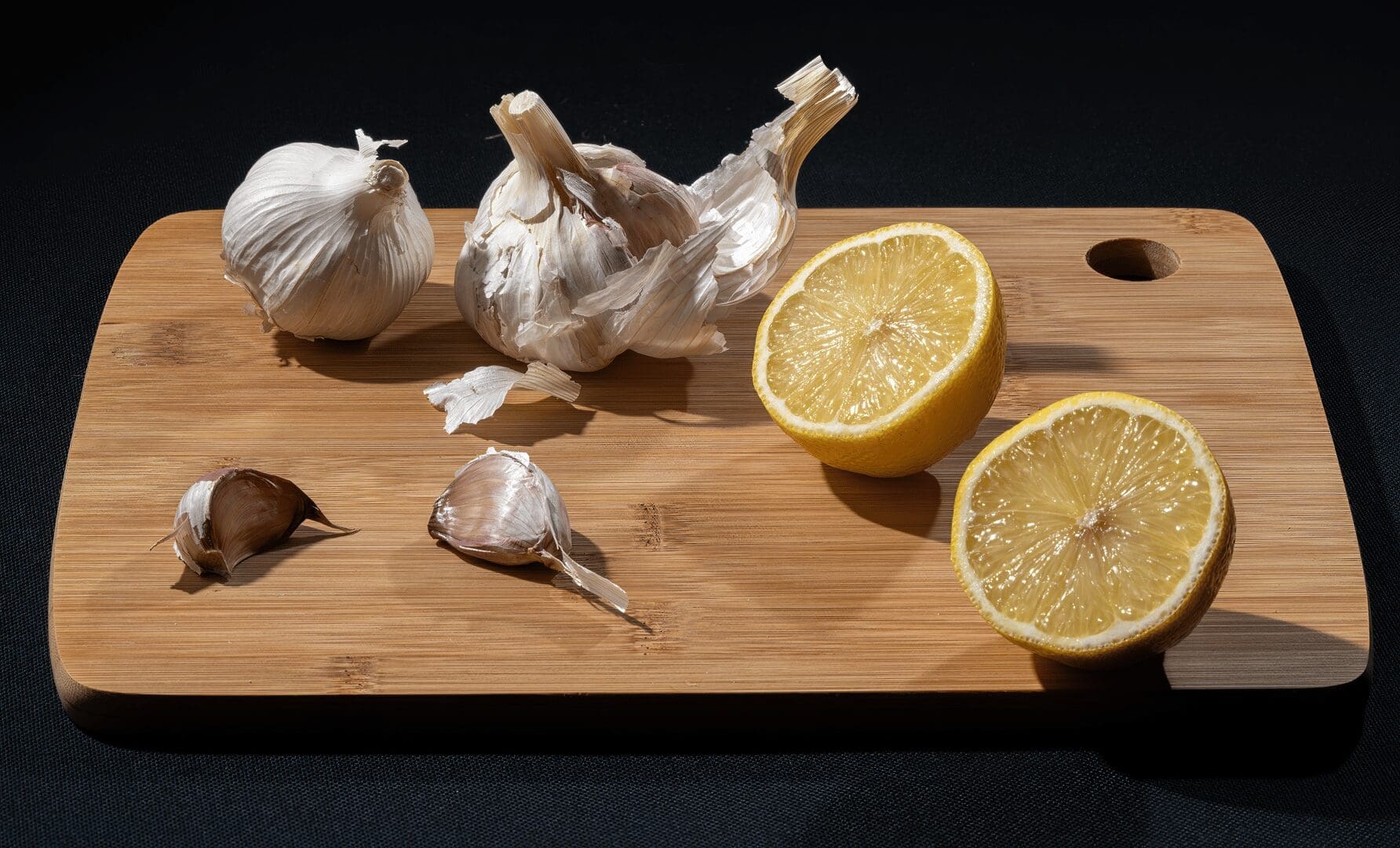 Fresh lemon and garlic on a wooden board, perfect for cooking inspiration.