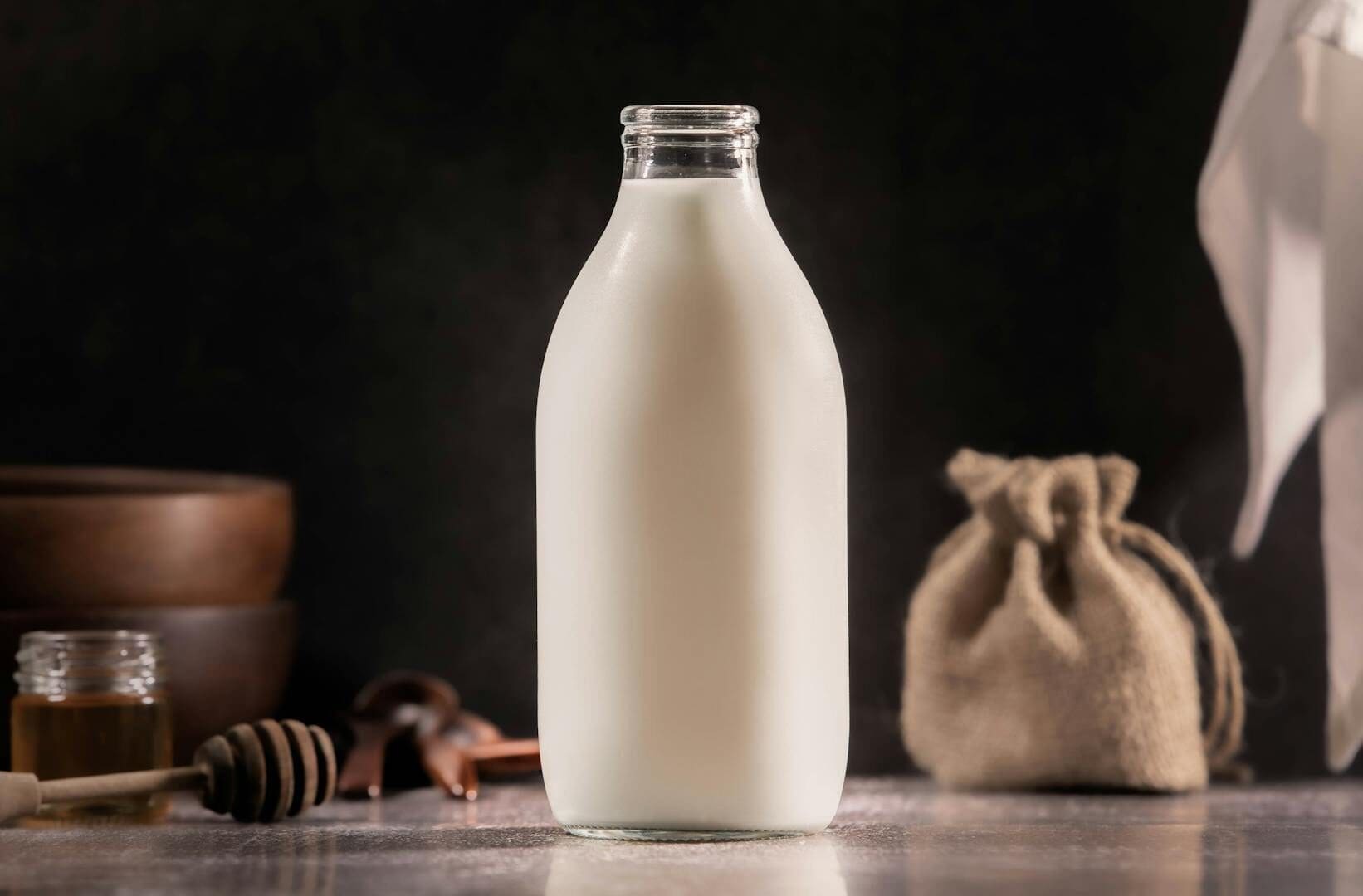 Aesthetic glass milk bottle with rustic kitchen elements in soft lighting.