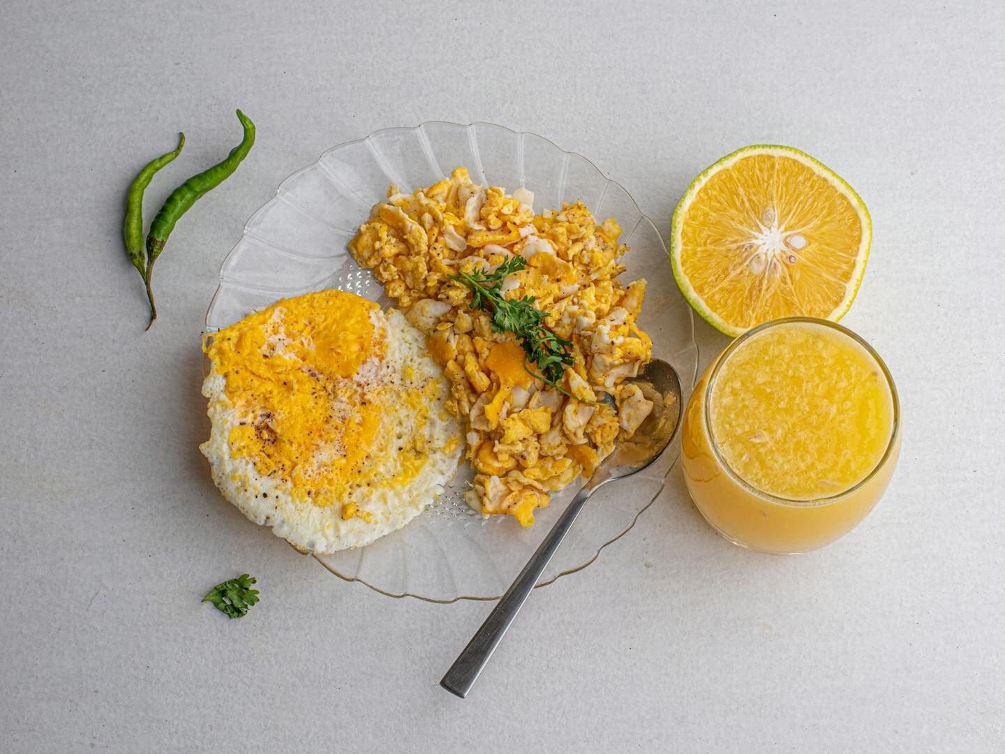 A hearty breakfast featuring fried eggs, scrambled eggs, and fresh orange juice.
