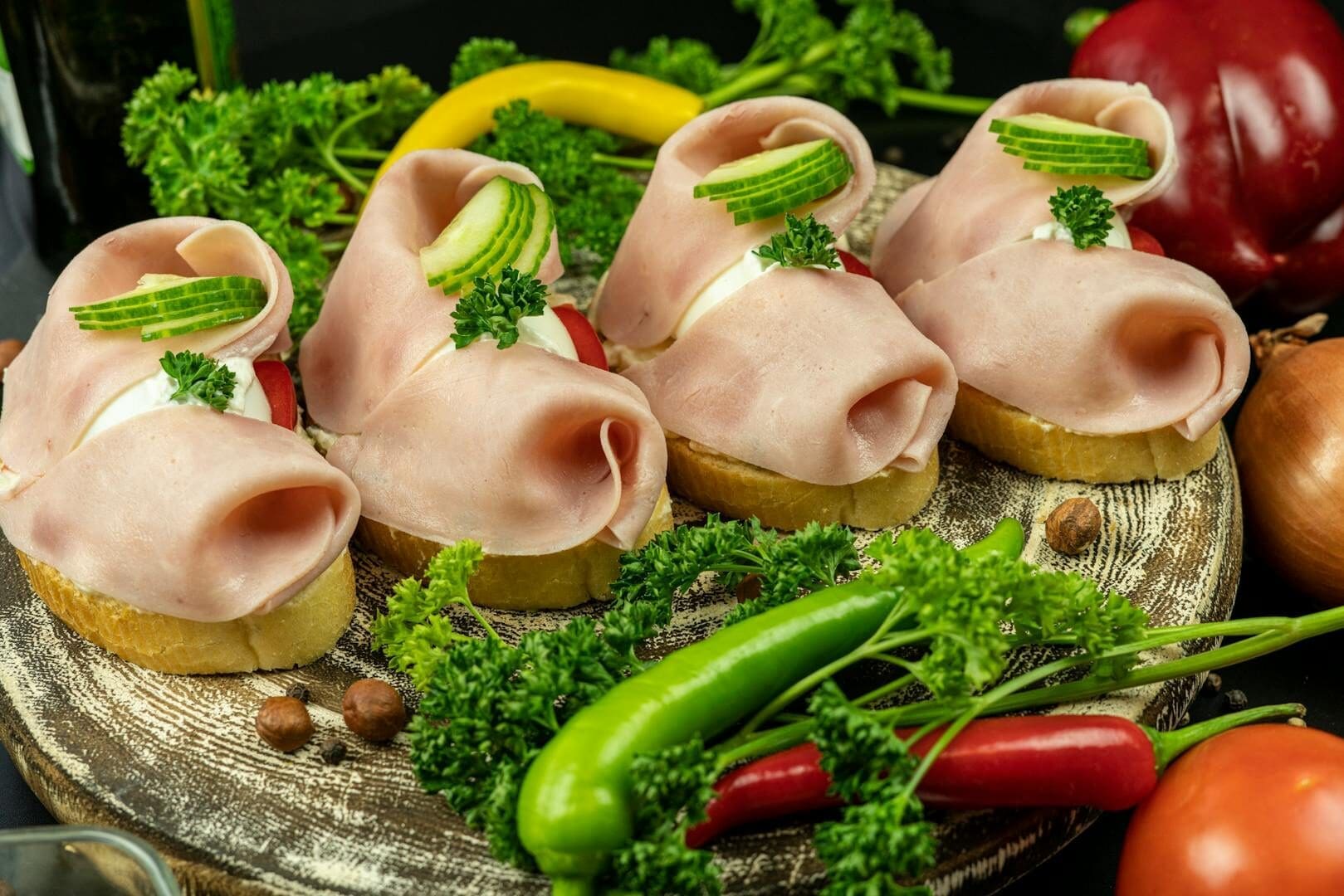 Delicious open-faced sandwiches with ham, cucumber, and parsley on rustic wooden plate.