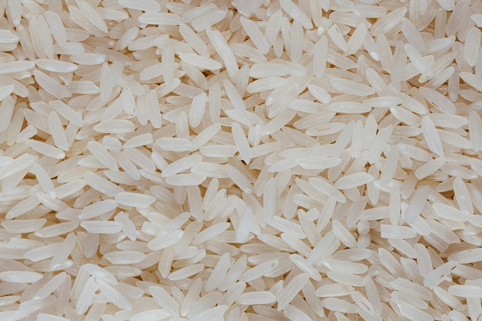 Detailed view of uncooked white rice grains, showcasing texture and pattern.